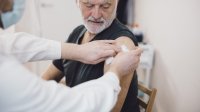 Vaccinatie oudere man krijgt prik van vrouwelijke arts