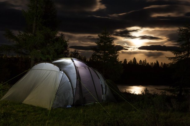 Camping tent in de nacht met de maan in de wolken