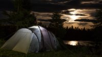 Camping tent in de nacht met de maan in de wolken
