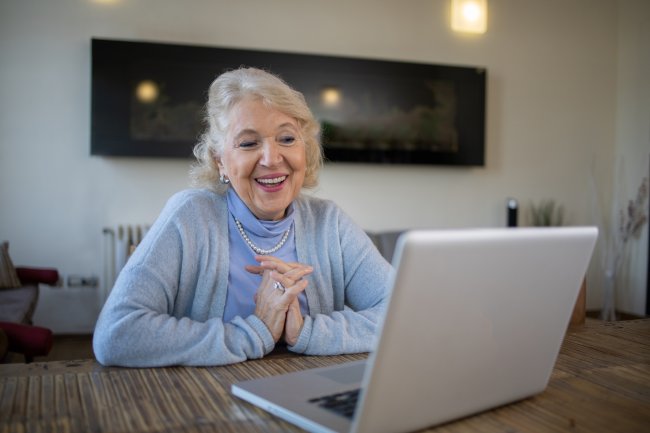 Oudere dame is blij achter haar laptop
