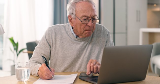 Oudere man werkt serieus achter laptop