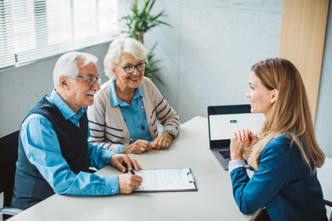 Makelaar in gesprek met senior stel aan de keukentafel