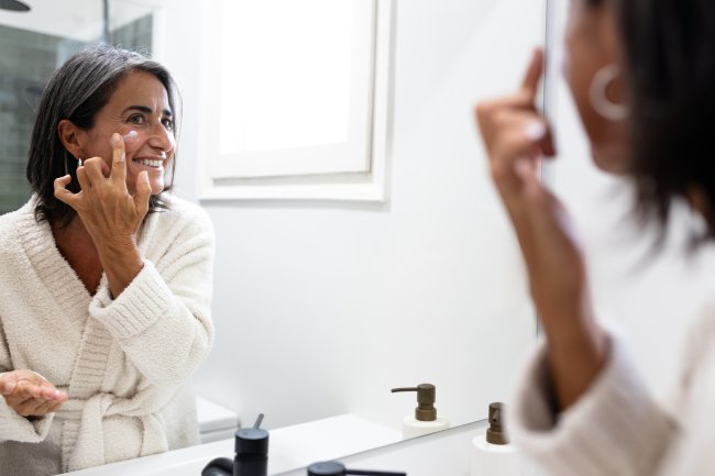 Vrouw doet creme op in de badkamer