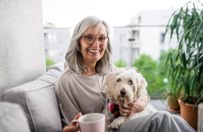 Vrouw zit met harige hond op schoot in de woonkamer