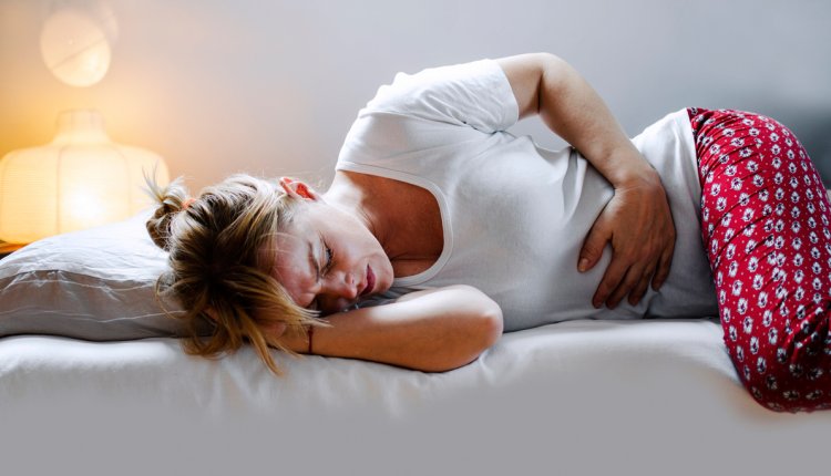 Vrouw met buikpijn in bed