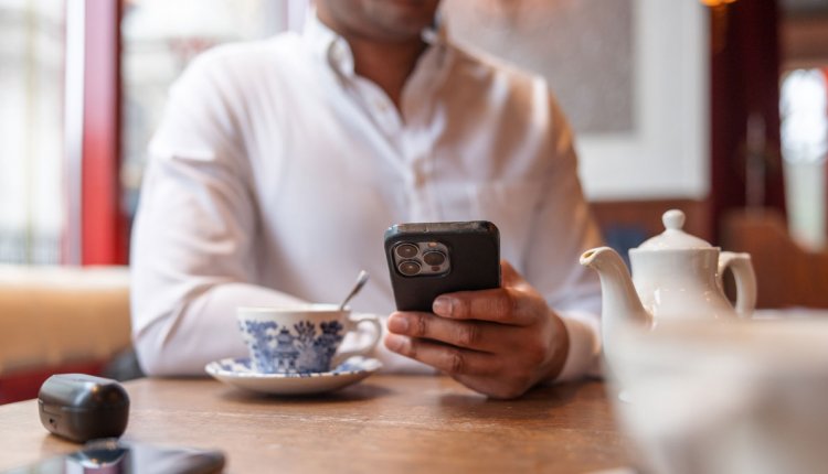 man aan tafel gebruikt iPhone