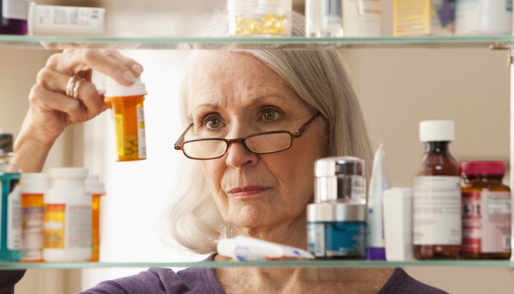 oudere vrouw kijkt in medicijnkastje