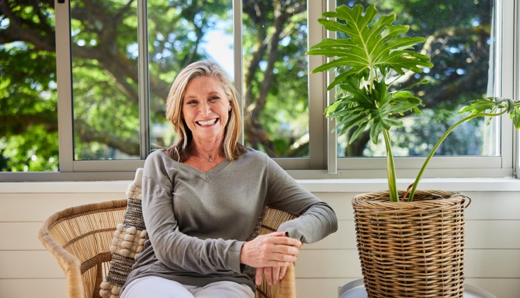 Blanke vrouw op stoel in de woonkamer met groene tuin