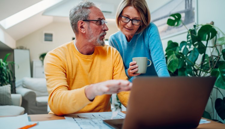 Hypotheek ouder paar bespreekt de cijfers met laptop