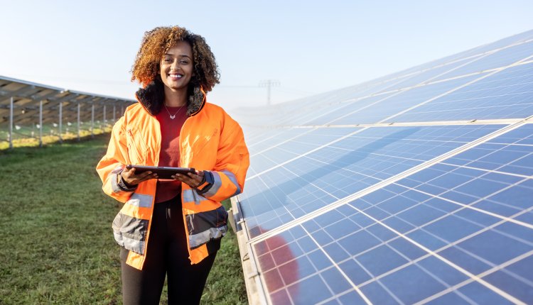 Vrouw staat naast zonnepanelen in een weiland