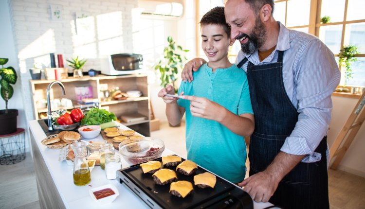 Hamburgers bakken vader en zoon in de keuken met kaas