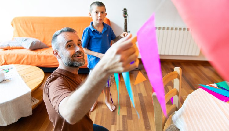 Man hangt slingers op in de woonkamer met zijn zoon