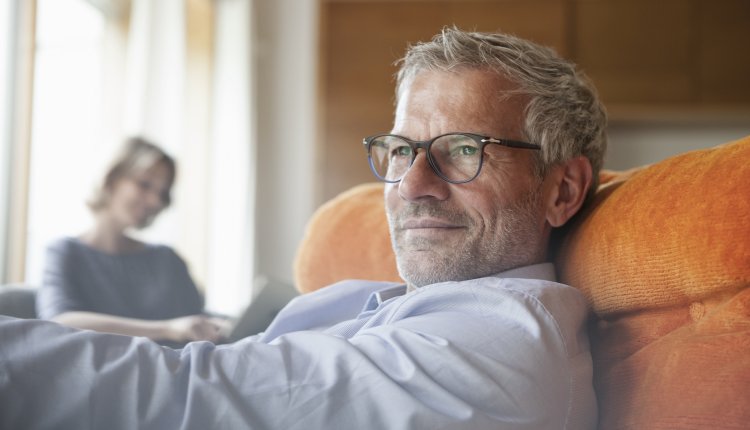 Oudere man zit ontspannen in fauteuil
