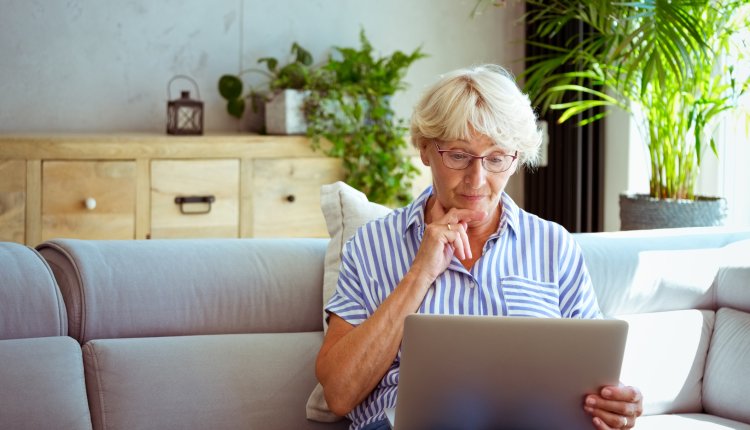 Uitkering in gevaar, vrouw kijkt bezorgd op laptop