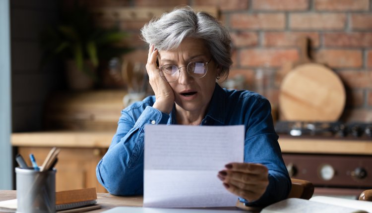 Oudere vrouw leest geschokt een brief
