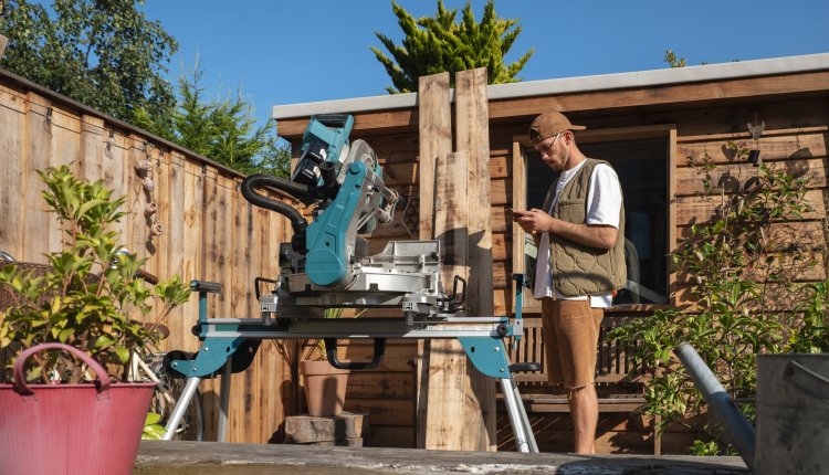 Man is bezig met hout zagen, schuur op de achtergrond