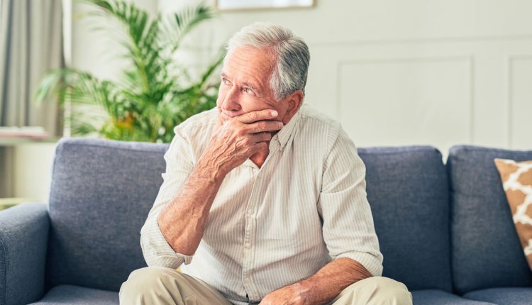 Man zorgelijk op de bank in zijn woonkamer