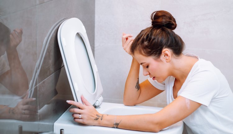 Jonge vrouw hangt over rand van het toilet