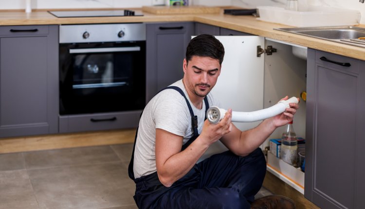 Werkende man is bezig afvoer van kraan te vervangen