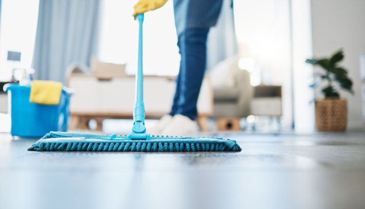 Schoonmaker doet de vloer met een mop