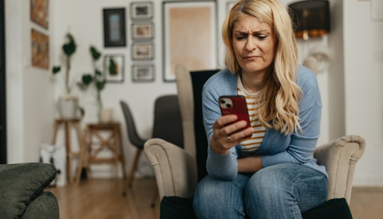Vrouw is boos, kijkt op haar telefoon in de woonkamer