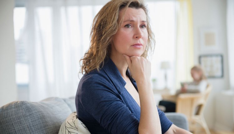 Vrouw zit op de bank kijkt zorgelijk