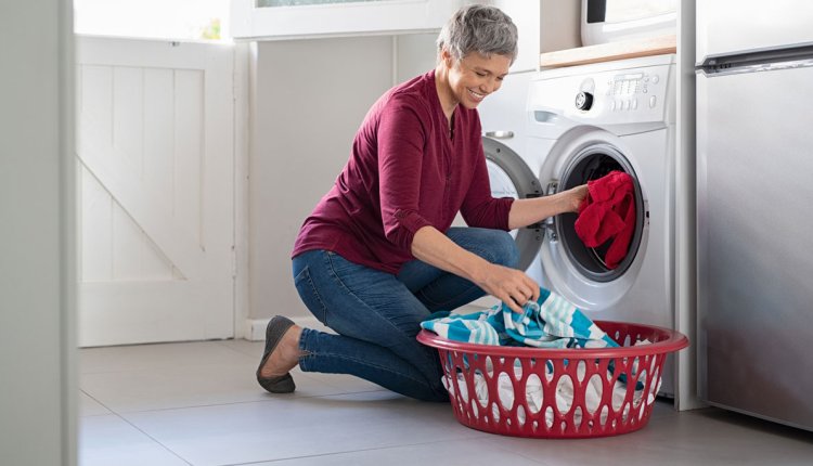 Vrouw doet kleding in de wasmachine