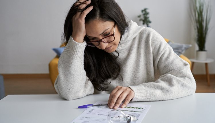 Vrouw bestudeert energierekening met bezorgd gezicht