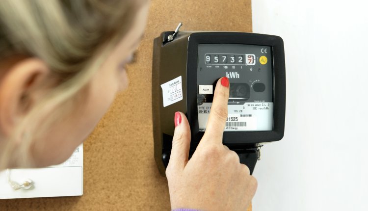 Vrouw wijst naar stroom meter