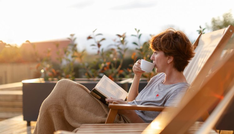 Vrouw drinkt een kop koffie in de ochtendzon