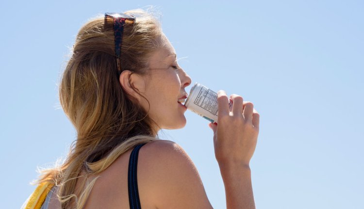 Vrouw drinkt in de warme zon een blikje fris
