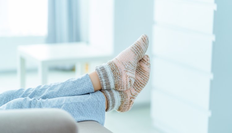 Vrouw met benen omhoog op de bank in warme sokken