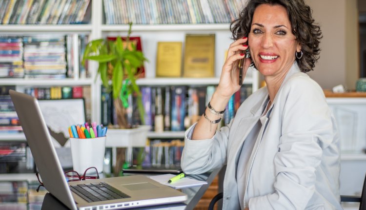 Knappe oudere vrouw aan de telefoon in haar eigen kantoor