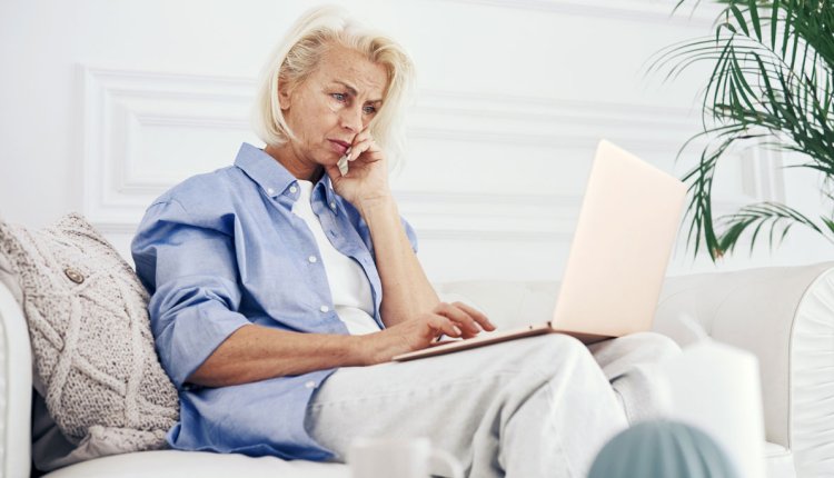 Vrouw op de bank zit op een computer te kijken