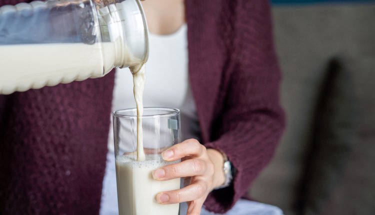 Vrouw schenkt melk in een groot glas