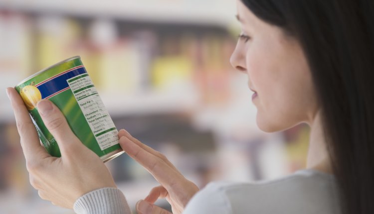 Vrouw leest etiket op een blik in de supermarkt