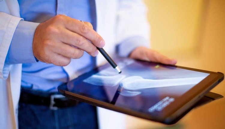 Dokter kijkt naar ipad met artrose foto