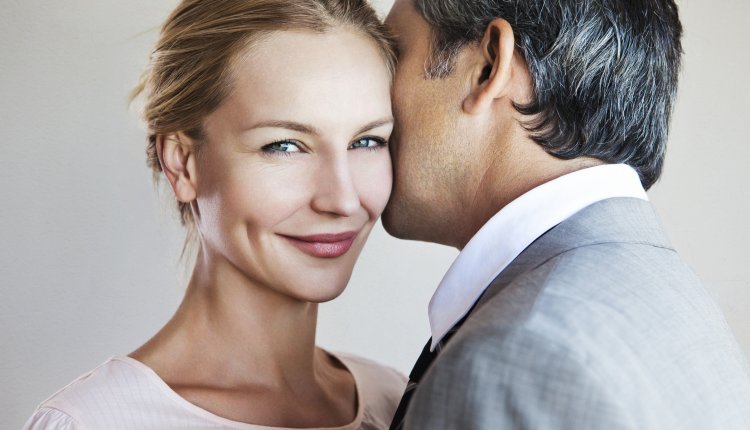 Man fluistert bij vrouw in het oor