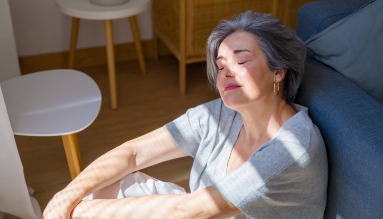 oudere vrouw zit binnen in de zon