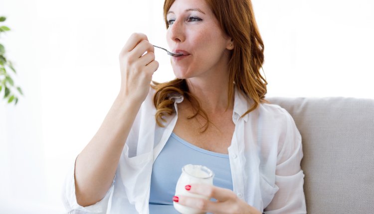 Vrouw eet crème fraîche op de bank