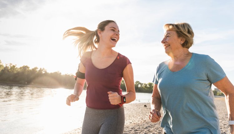 Moeder en dochter rennen in de zon met activity tracker om de pols