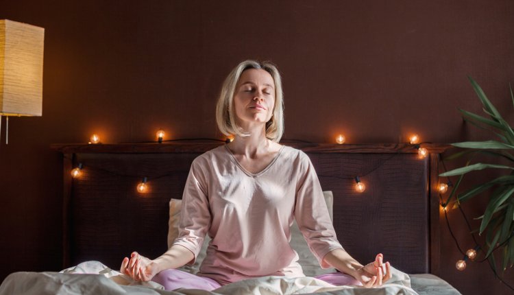 Vrouw doet yoga-oefening op bed voor het slapengaan