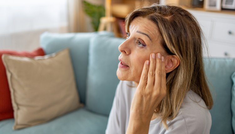 Vrouw met hand op haar oor, ze wordt gek van piep