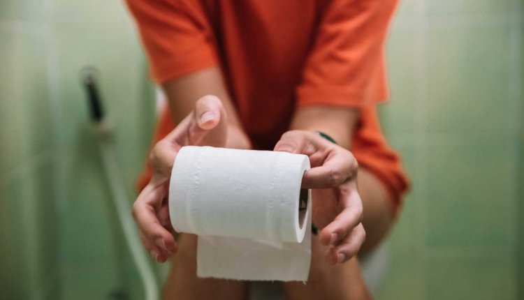 Vrouw op toilet met toiletrol