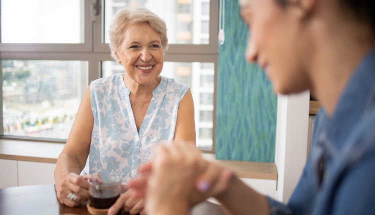 oudere vrouw drinkt koffie met mantelzorger