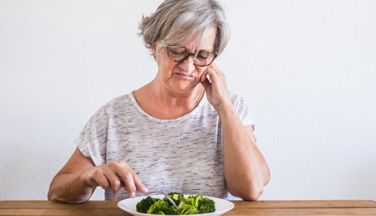vrouw kijkt vies naar haar bord met eten