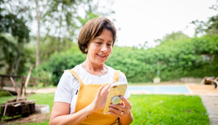Vrouw met smartphone in de tuin