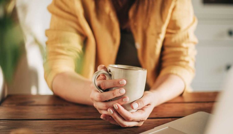 Vrouw drinkt koffie achter laptop