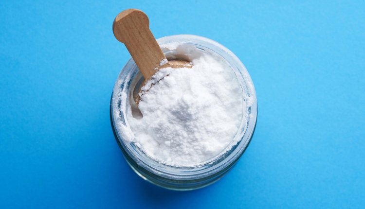 Een glazen potje met baking soda op een blauwe achtergrond