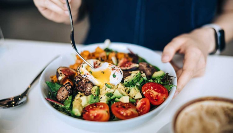 Vrouw eet salade met ei